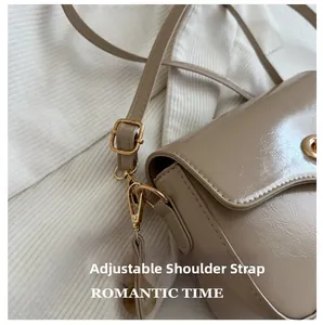 Détail de la bandoulière réglable avec boucle dorée sur le sac en cuir verni beige plissé