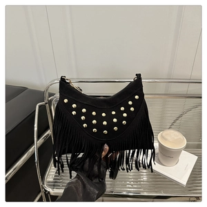 Detail of black suede crossbody bag featuring golden rivets and elegant tassel fringe