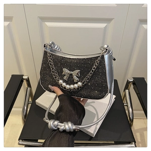 Détail du sac à main noir pailleté avec breloque papillon et chaîne en perles fines