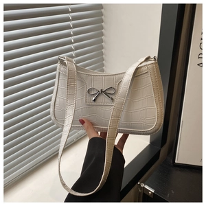 Close-up of white crocodile pattern shoulder bag with a silver metal bow buckle detail