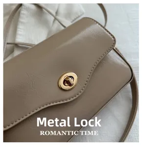 Détail du fermoir doré rotatif sur un sac à main beige en cuir à plis fins