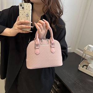 Pink dome shell handbag with woven texture and silver hardware held by a model