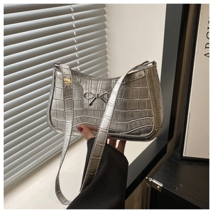 Detail of silver crocodile pattern shoulder bag with metallic bow and zipper closure