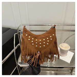Detail of brown suede crossbody bag featuring gold studs and long fringe tassels