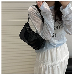 Close-up of black glossy crescent underarm bag with sleek metal zipper detail