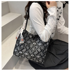 Ethnic tote bag with geometric print and decorative silk scarf shown on shoulder