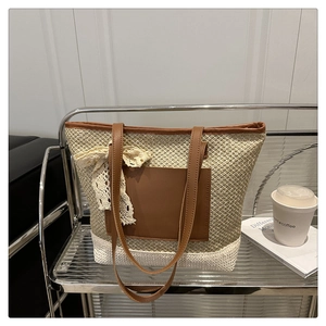 Detail of woven straw tote bag featuring brown faux leather trim and lace bow charm