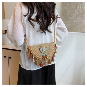 Detail of bohemian straw crossbody bag featuring colorful tassels and ethnic beadwork