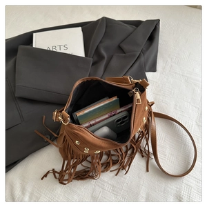 Detail of brown suede crossbody bag with long fringes and golden stud accents