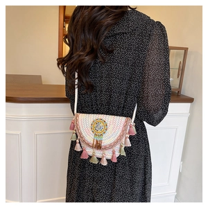 Detail of bohemian woven crossbody bag with colorful embroidery and cotton tassels