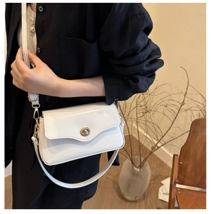 Petit sac carré blanc minimaliste avec fermoir doré porté sur une chemise noire