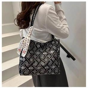 Detailed view of tote bag featuring ethnic embroidery, woven straps and decorative scarf