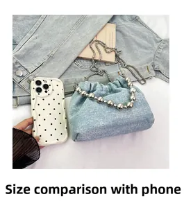 Size comparison of light blue denim bucket bag with silver pearls and a mobile phone
