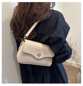 Détail du sac carré beige avec un fermoir rotatif doré vintage et du cuir mat