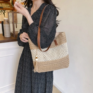 Large straw tote bag with leather straps and tassel, perfect for summer beach vacations