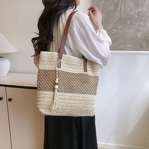 Summer straw tote bag with brown leather straps and tassels for beach vacations