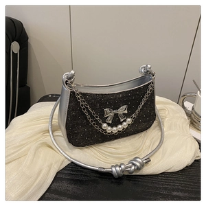 Détail du sac noir pailleté avec boucle papillon argentée et chaîne de perles décorative