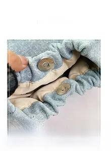 Detail of magnetic snap closure on light blue denim bucket bag with sparkling rhinestones