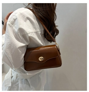 Sac baguette marron en similicuir avec fermoir rotatif doré porté à l'épaule