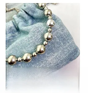 Detail of silver beaded handle and light blue denim drawstring bag with rhinestones