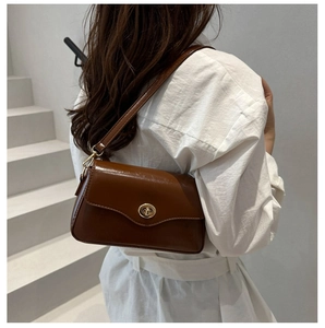 Détail d'un sac bandoulière carré en cuir marron vintage avec un fermoir doré élégant