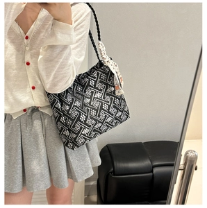 Detail of ethnic tote bag featuring geometric patterns and stylish silk scarf accessory