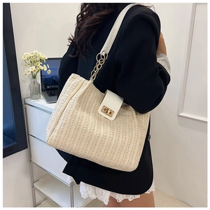 Detail of woven straw tote bag featuring white leather trim and gold twist-lock closure