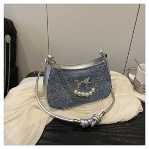 Détail du sac en jean avec bordures argentées et pendentif papillon avec perles