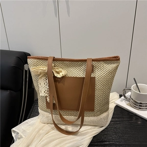 Beige woven straw tote bag with brown leather handles and lace bow on dark table