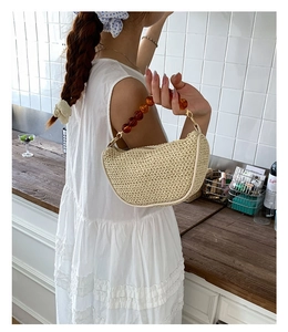Detail of hand-woven beige straw bag featuring a retro amber bead handle and texture