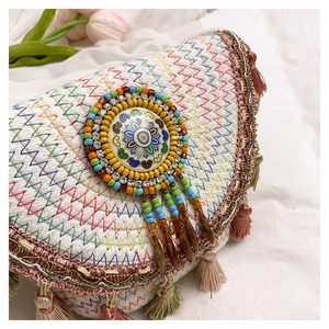 Detail of woven boho bag featuring colorful embroidery, mandala beadwork, and fringe accents