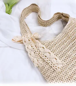 Close-up of woven straw tote bag with delicate white lace bow detail and fabric lining