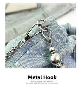 Detail of silver lobster clasp and metal chain on light blue denim bag with rhinestones