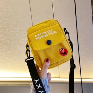 Détail de la sacoche jaune en toile avec sangle réglable et écusson de dessin animé