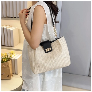 Close-up of woven tote bag with black leather flap and golden twist lock closure