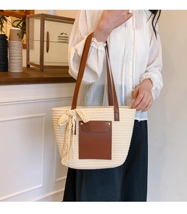 Détail d'un sac cabas en paille beige avec poche en cuir marron et nœud en dentelle doux