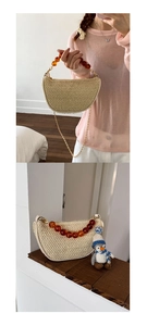 Detail of a semi-circular straw bag with amber resin beads and a golden chain strap