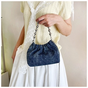Detail of denim bucket bag featuring silver bead handle and sparkling rhinestone accents