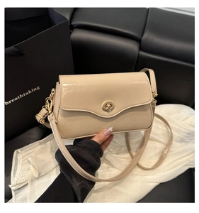 Détail du sac carré en cuir crème avec fermoir rotatif doré et finition lisse et brillante
