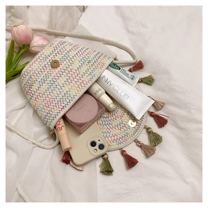 Close-up of colorful woven crossbody bag with vibrant wave patterns and boho fringe details