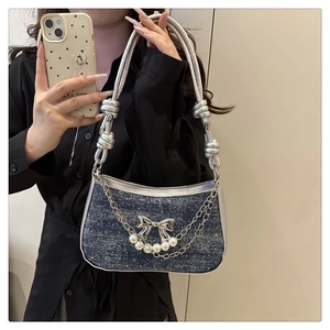 Détail du sac en jean avec fermoir nœud argenté, breloques perles et chaînes en métal