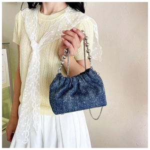 Detail of blue denim bucket bag featuring silver bead handle and chain strap