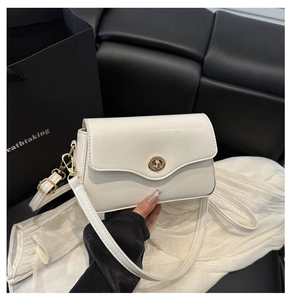 Détail d'un sac à bandoulière blanc en cuir avec fermoir rotatif doré et bandoulière chic