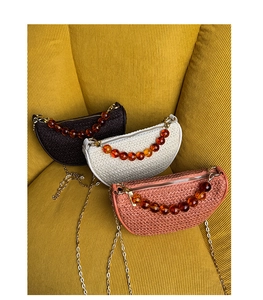 Three woven crescent bags with amber bead handles and gold chain straps on striped fabric