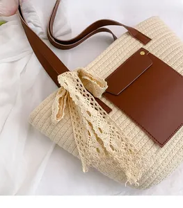 Gros plan d'un sac cabas tressé avec poignées en cuir marron et ruban en dentelle élégant