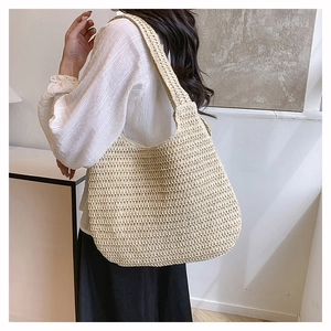 Macro detail of the beige woven straw beach bag showing handmade crochet texture and strap