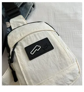 Dettaglio della borsa da petto in nylon bianco sporco con cerniera e logo