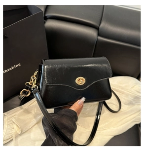 Détail d'un élégant sac à bandoulière en cuir verni noir avec fermoir doré