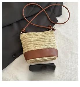 Détail d'un sac bandoulière tissé beige avec base en cuir marron et fine lanière en cuir