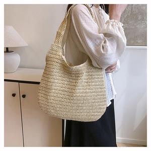 Detail of a beige woven straw tote bag featuring a hollow bohemian knit pattern